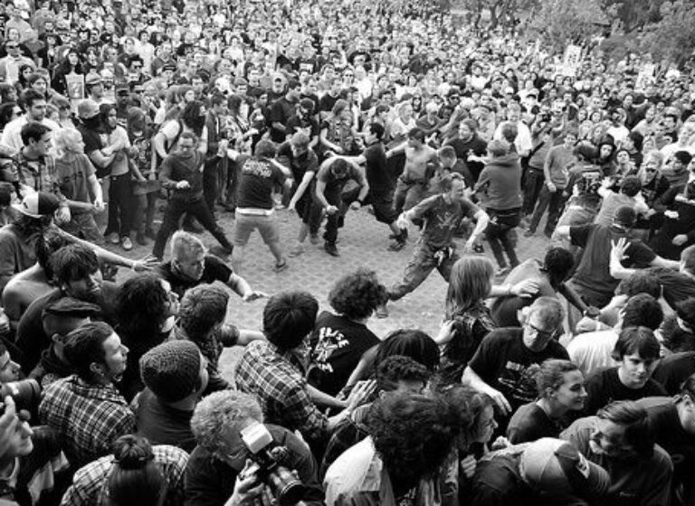 Grote moshpit met dansende en elkaar ondersteunende concertbezoekers